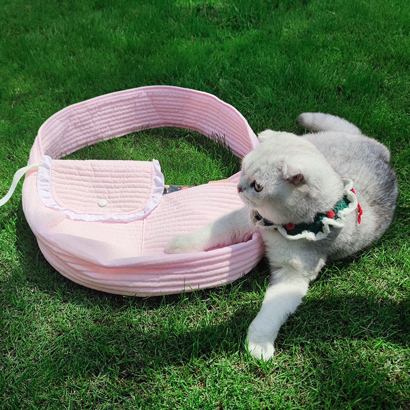 Gato tumbado junto a una mochila transportín rosa